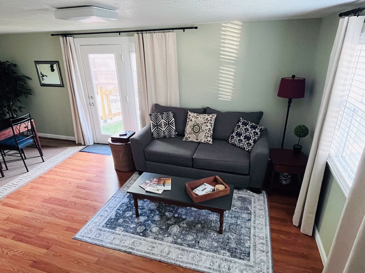 Where to Stay in Knoxville, TN (and the Airport Airbnb I'd Book Again) 5 Parkside Loft living room in Alcoa, Tennessee, with a gray sofa, coffee table, rug and French doors to the backyard