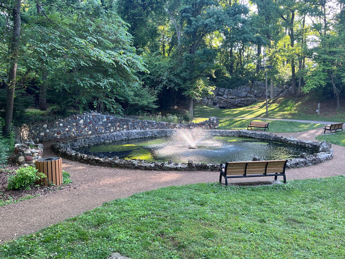 Where to Stay in Knoxville, TN (and the Airport Airbnb I'd Book Again) 8 A stone-edged pond with a fountain and a park bench in Springbrook Park, Alcoa, Tennessee